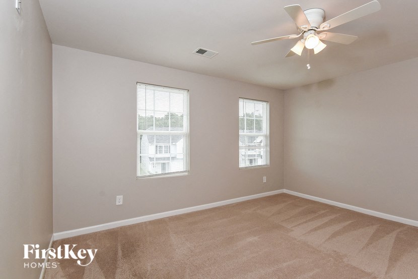 an empty room with a ceiling fan and two windows
