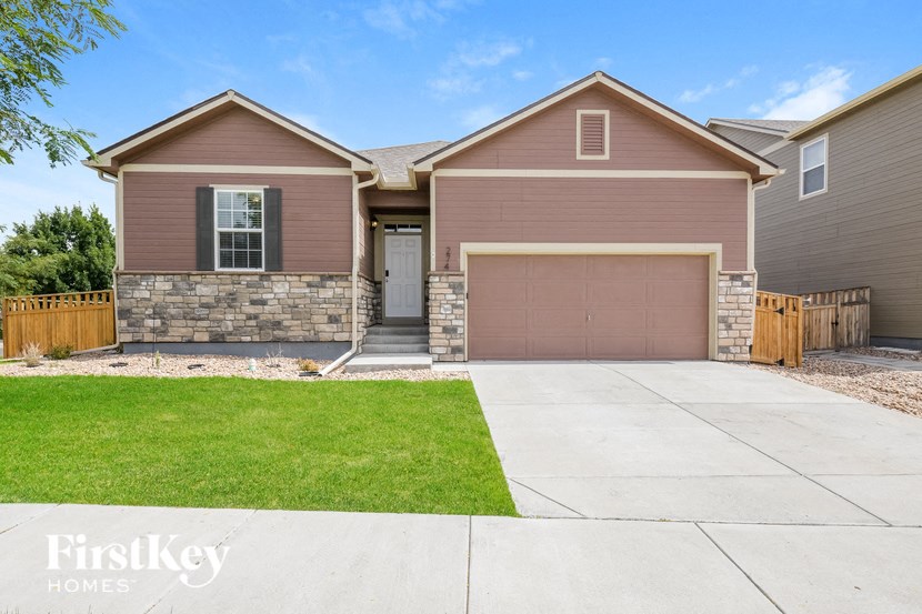 A house with a brown garage door and a stone wall.