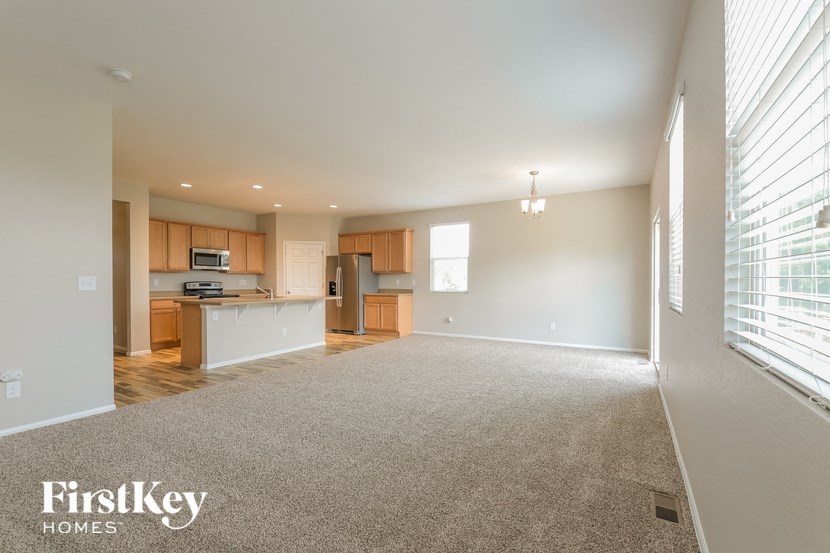 A spacious living room with a kitchenette in the background.