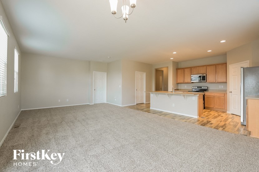 A spacious living room with a kitchenette in the background.