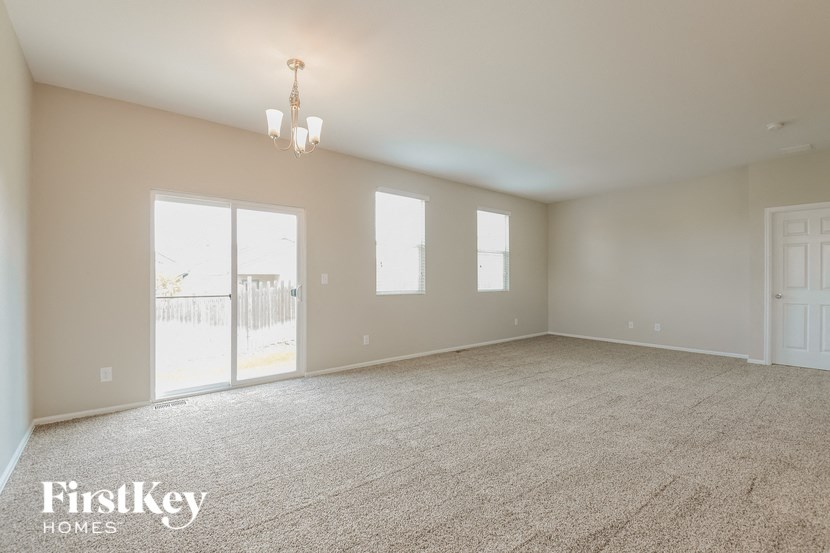 A spacious room with a carpeted floor and a chandelier hanging from the ceiling.