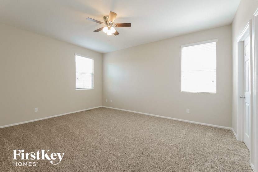 A spacious room with a carpeted floor and a ceiling fan.