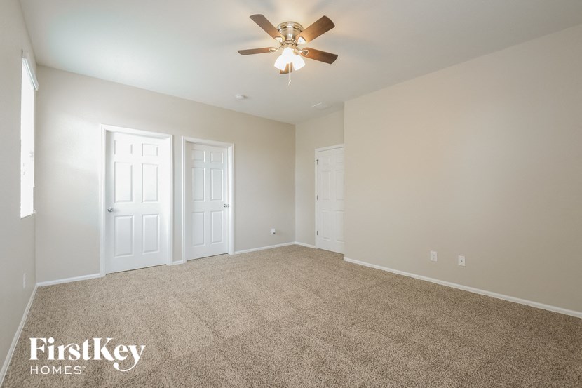 A spacious room with a carpeted floor and a ceiling fan.