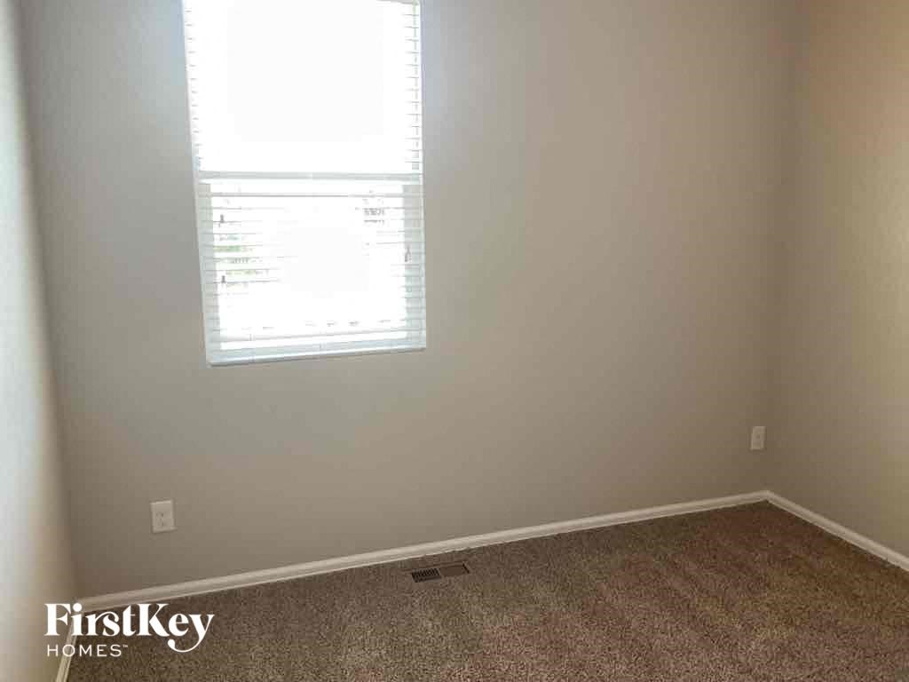 A room with a window and a carpeted floor.