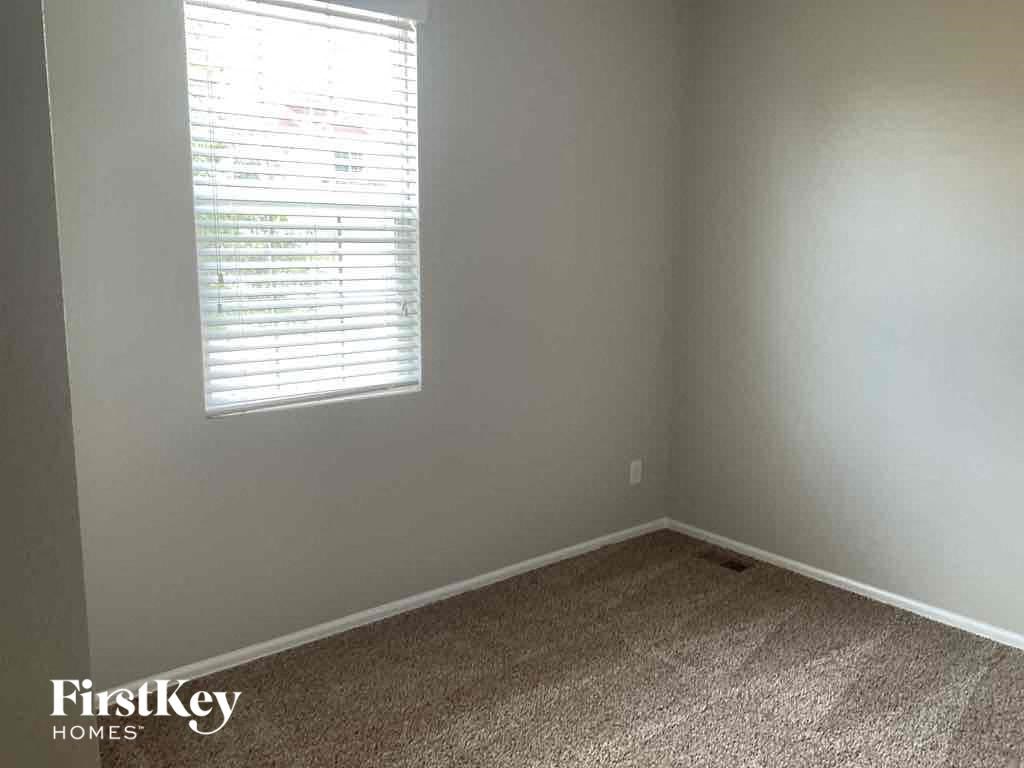 A room with a carpeted floor and a window with blinds.
