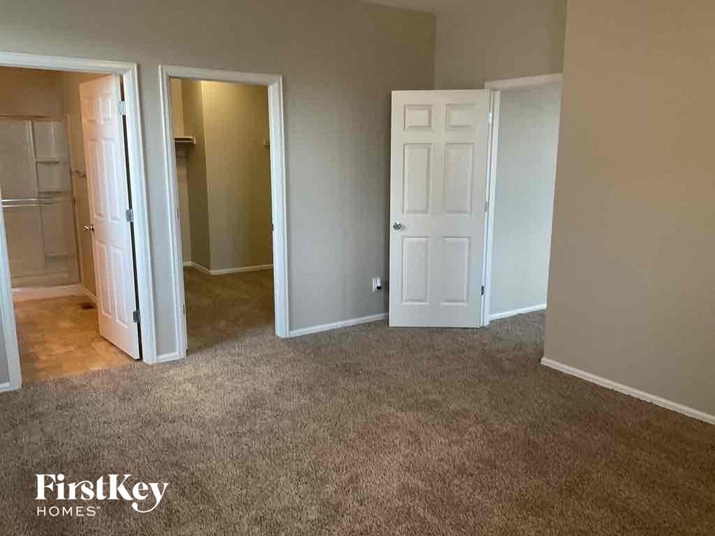 A carpeted room with a white door and a white closet.