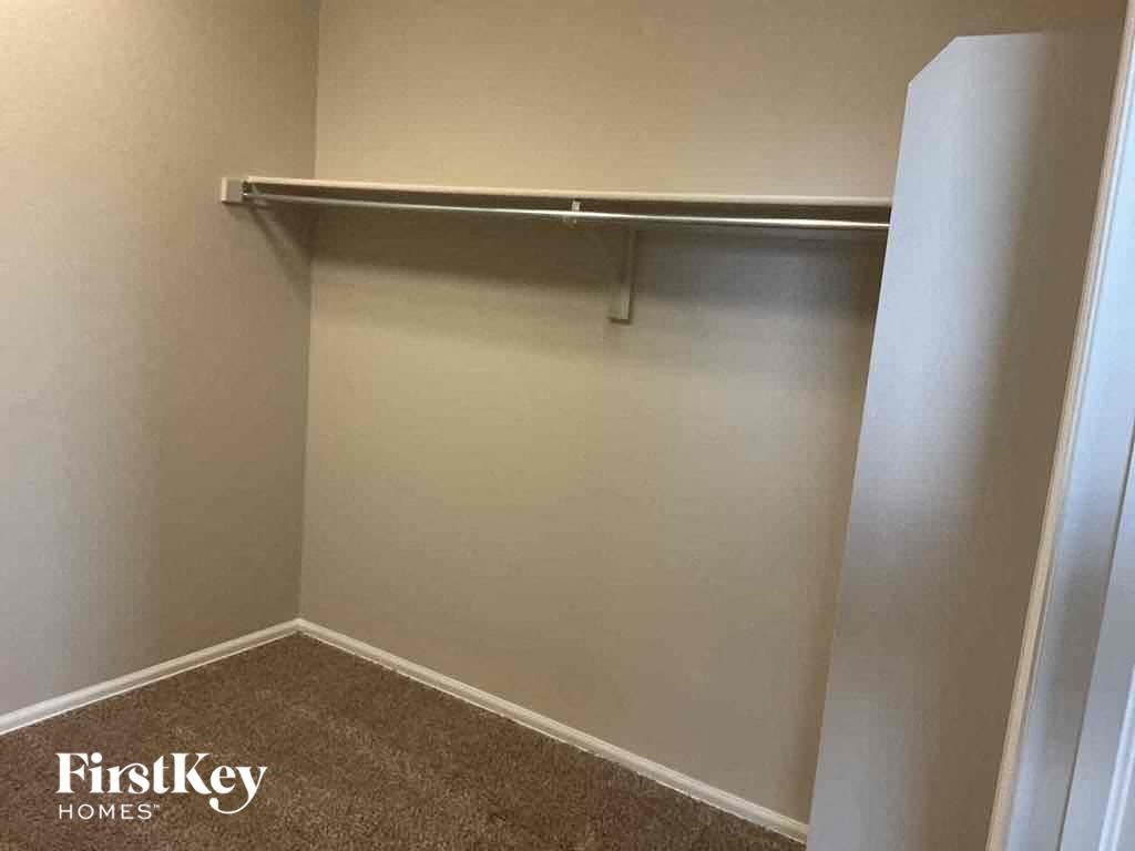 A room with a white wall and a metal shelf.