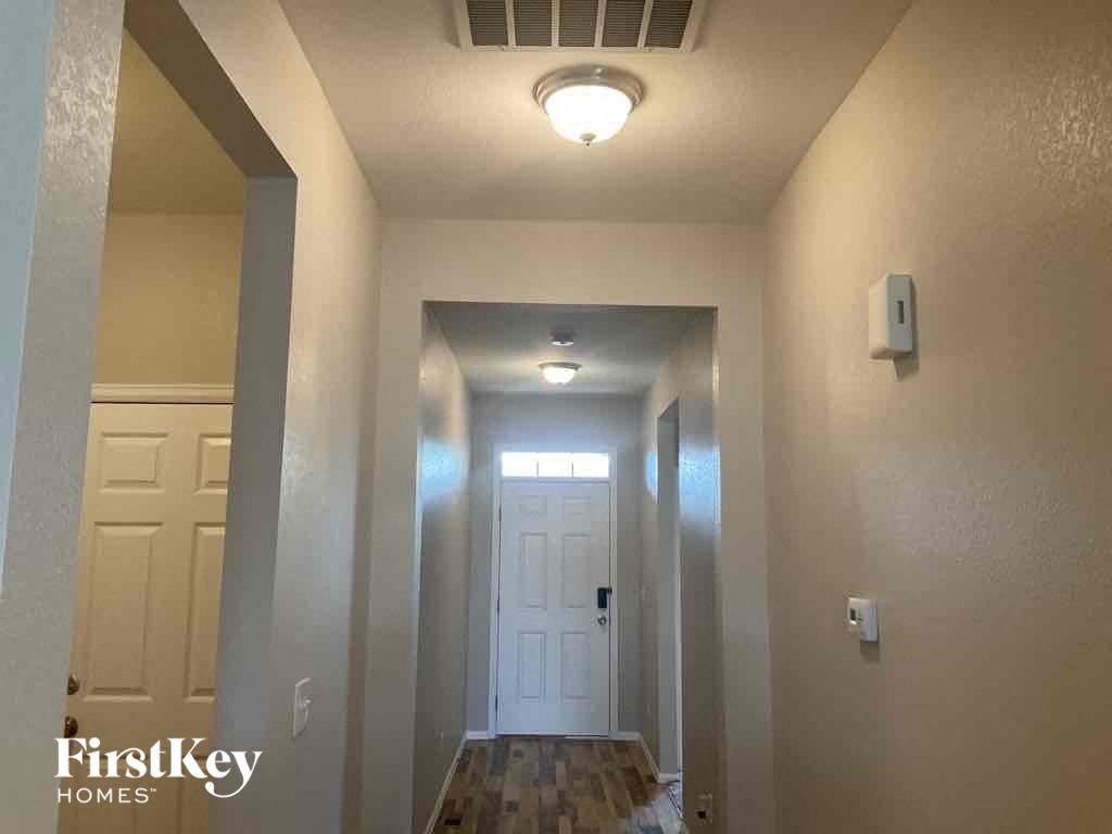 A hallway with a light on the ceiling and a door at the end.