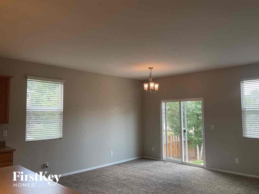 A room with a carpet floor, a chandelier, and a sliding glass door leading to a backyard.