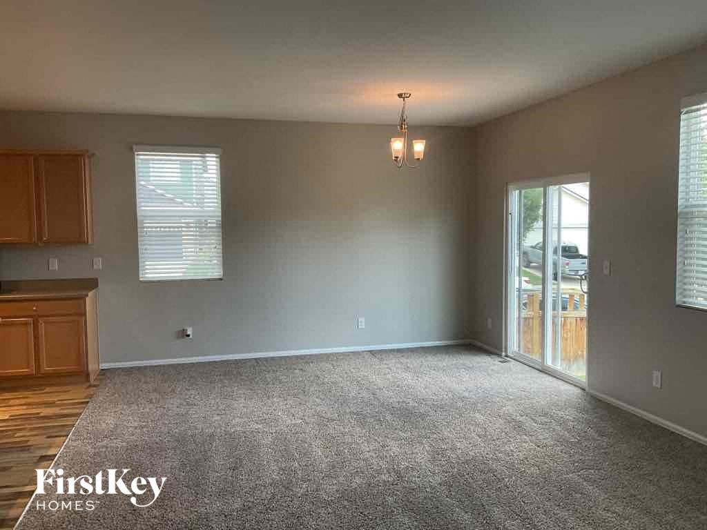 A spacious room with a grey carpet and wooden cabinets.