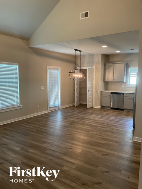 A spacious room with wooden flooring and a chandelier hanging from the ceiling.