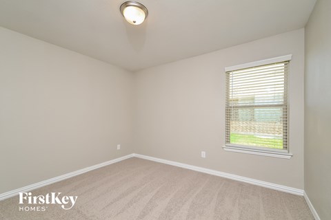 the spacious living room with a large window and carpeted flooring