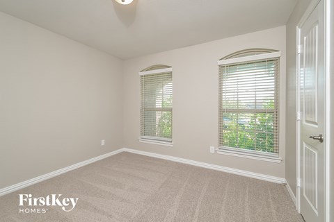 a bedroom with a carpeted floor and two windows