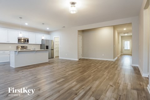 an open kitchen and living room with wood floors and white cabinets