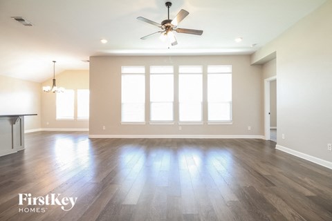 an empty living room with wood floors and a ceiling fan