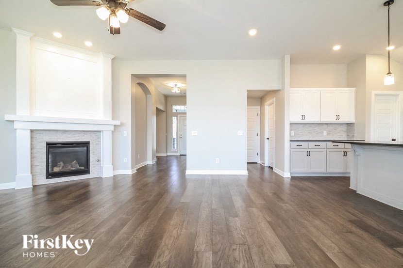 a living room with a fireplace and a kitchen with white cabinets
