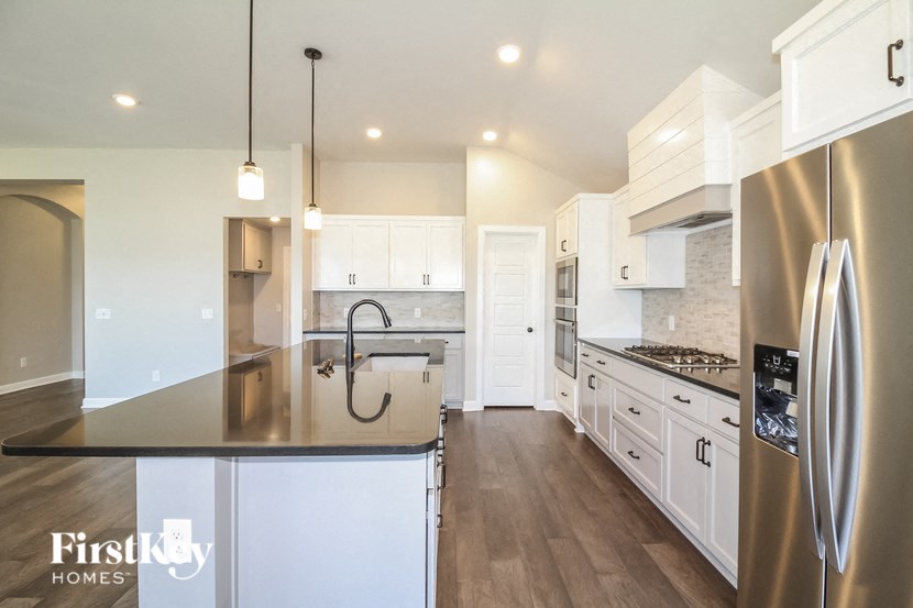 a large kitchen with stainless steel appliances and white cabinets