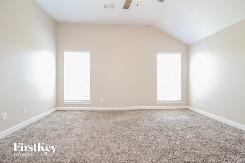 an empty room with carpet and two windows