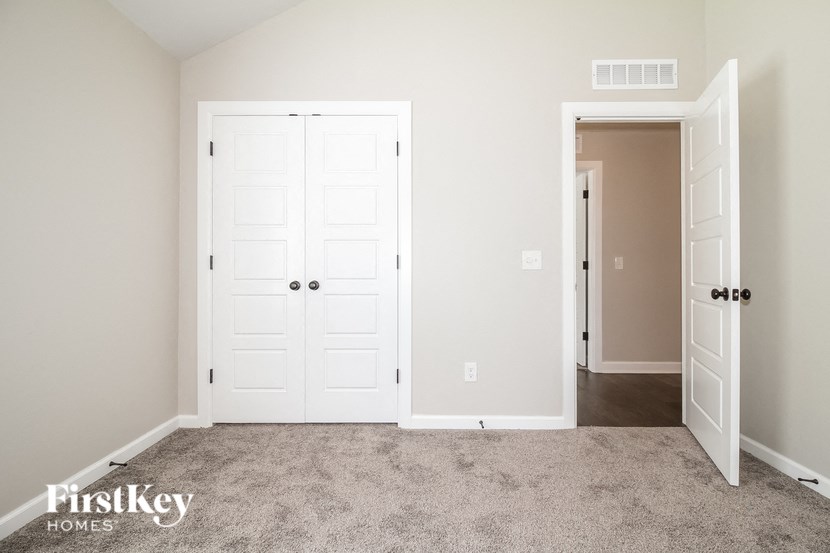 a clean carpeted room with two white doors and a closet