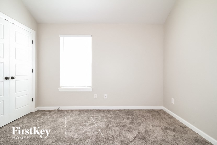 a carpeted room with a white door and a window