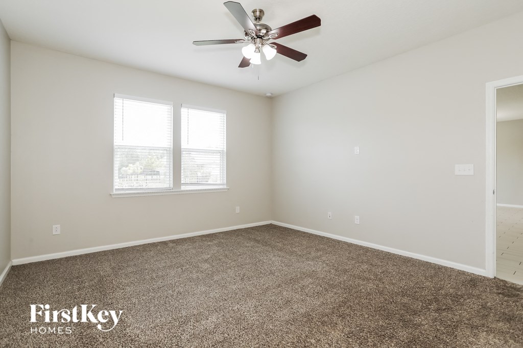 the spacious living room with ceiling fan and carpet