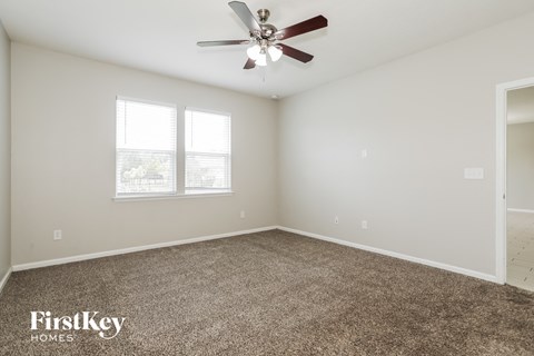 the spacious living room with ceiling fan and carpet