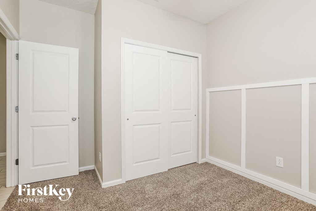 a bedroom with two closets and two doors and a carpeted floor