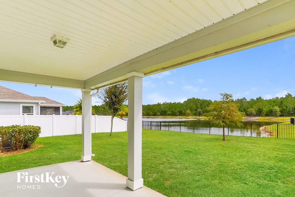 a covered porch with a view of a pond and a house
