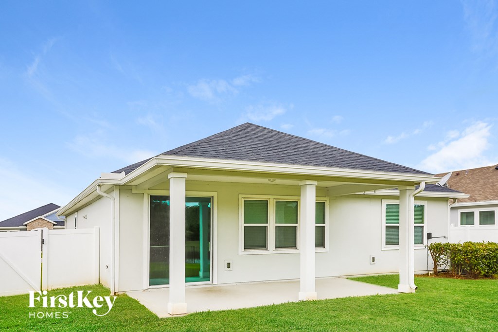 a small white house with white pillars and a green lawn