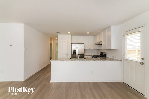 the living room and kitchen of an apartment with white cabinets