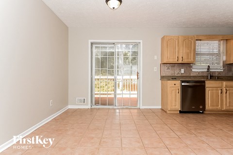 A kitchen with a black dishwasher and wooden cabinets.