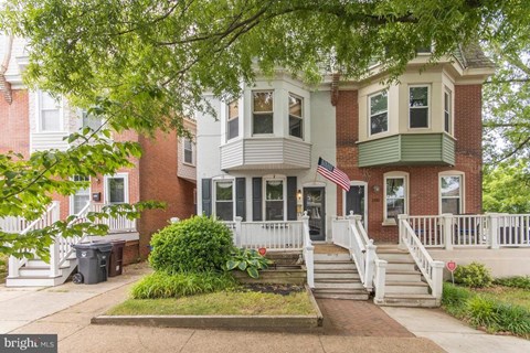 the front of a red brick house with a porch and a flag