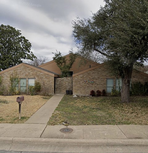a brick house with a tree and a sidewalk