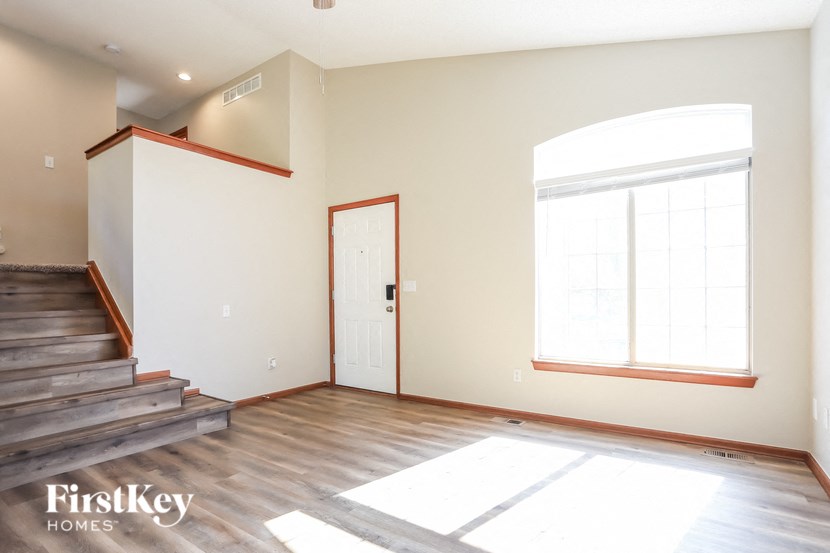 an empty living room with a staircase and a window