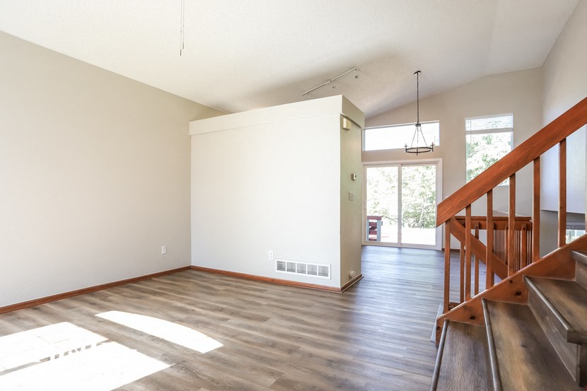 an empty living room with wood floors and a staircase