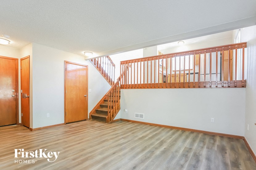 the living room of an empty house with wooden floors and a staircase
