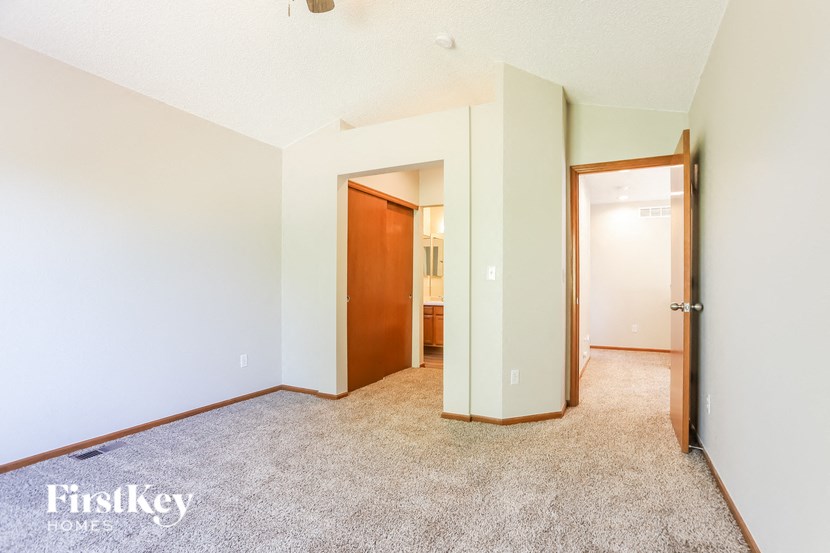 a bedroom with a carpeted floor and a door to a bathroom