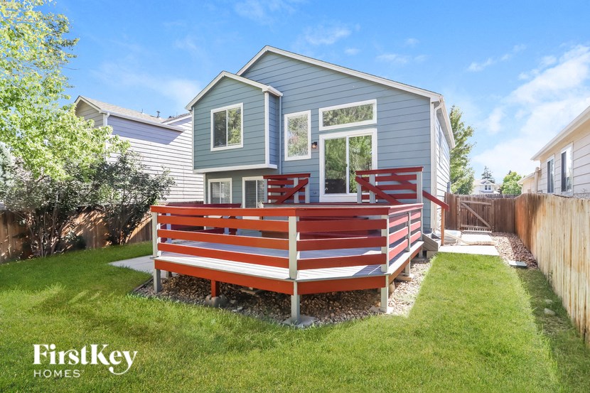 a deck with a wooden bench in front of a blue house