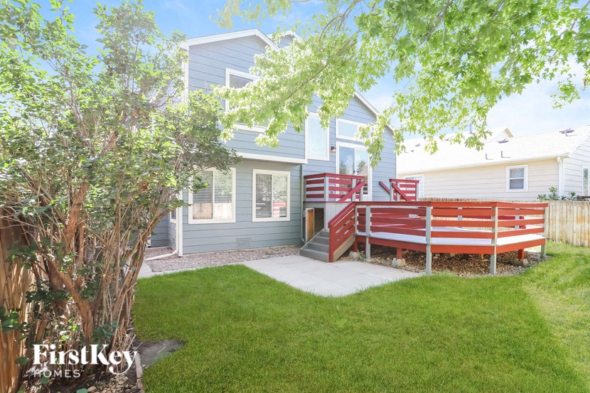a backyard with a red bench and a blue house