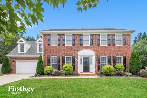 a brick house with black shutters and a green lawn