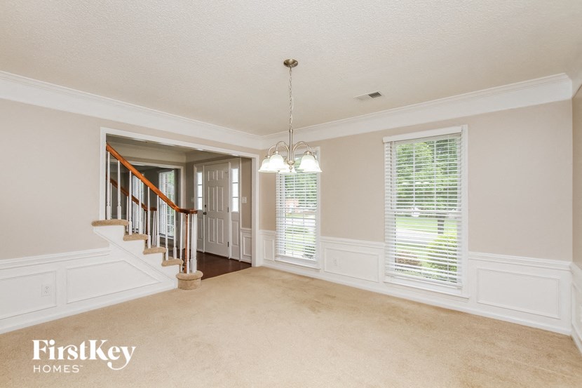 an empty living room with a staircase and a window
