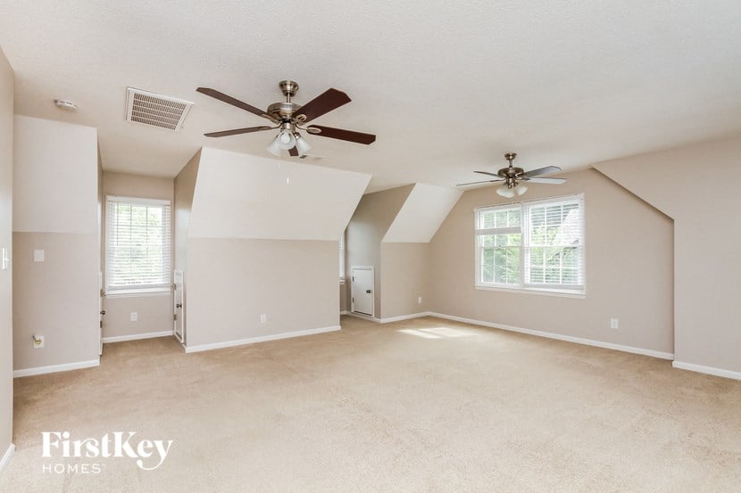 the spacious living room with ceiling fans and carpeting