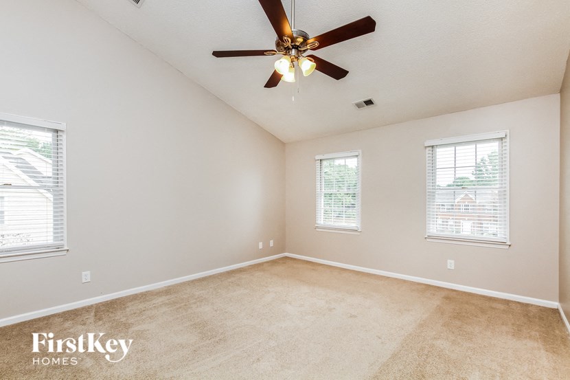 the master bedroom has a carpeted floor and a ceiling fan