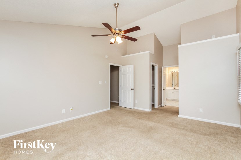 an empty living room with a ceiling fan and a door to a bathroom