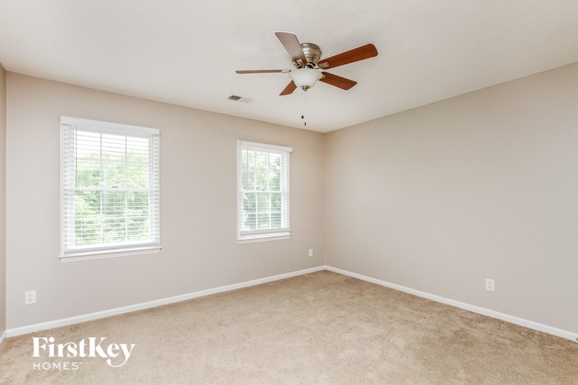 a bedroom with a ceiling fan and two windows