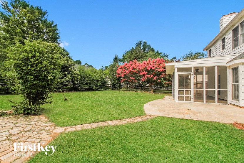 a backyard with a green lawn and a house with a patio
