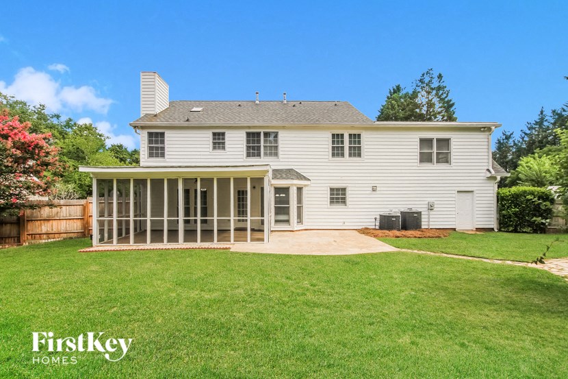 a screened porch in the back of a white house