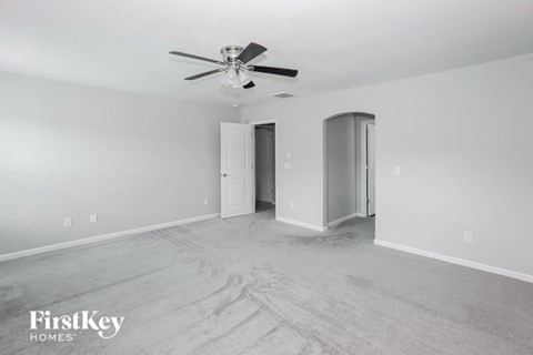 a empty living room with a ceiling fan and white walls