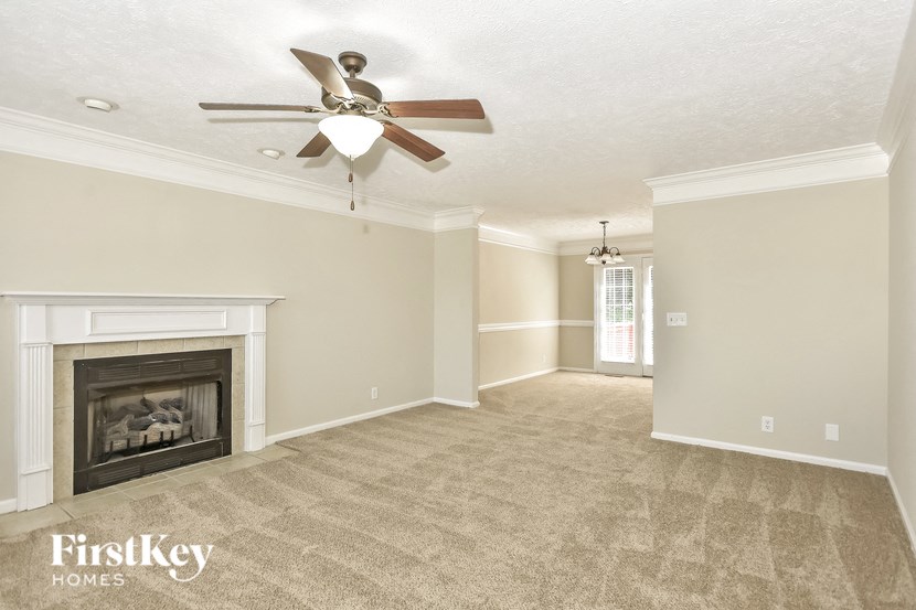 an empty living room with a ceiling fan and a fireplace