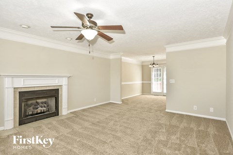 an empty living room with a ceiling fan and a fireplace